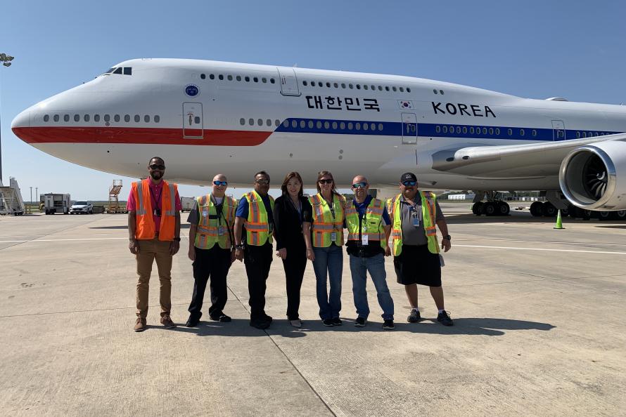 Houston Airports employees smile for a photo with a plane from South Korea