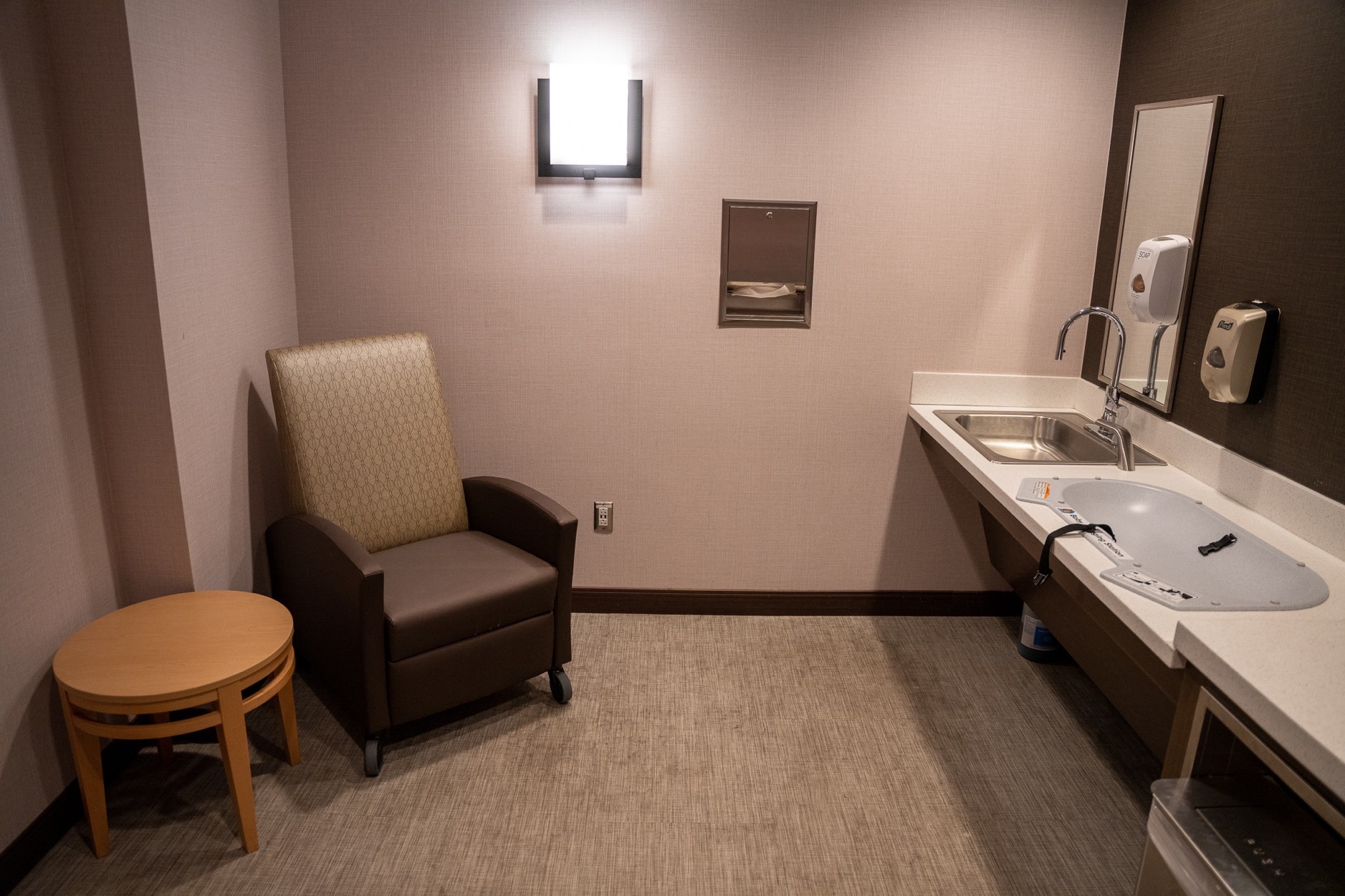Photo shows one of the mothers rooms available to parents traveling with young children. A baby changing station, sink, trashcan and comfortable seating are available for free. 