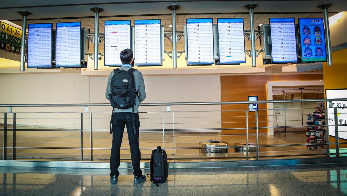 Man looks up at flight board at Bush Intercontinental Airport