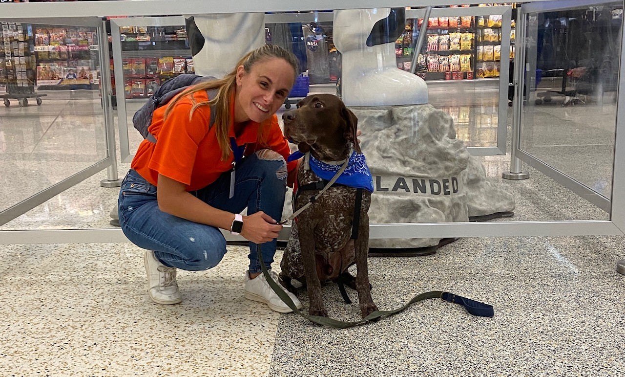 Therapy dog handler, Jill, poses for a photo at Bush Airport with Copper, a therapy dog.