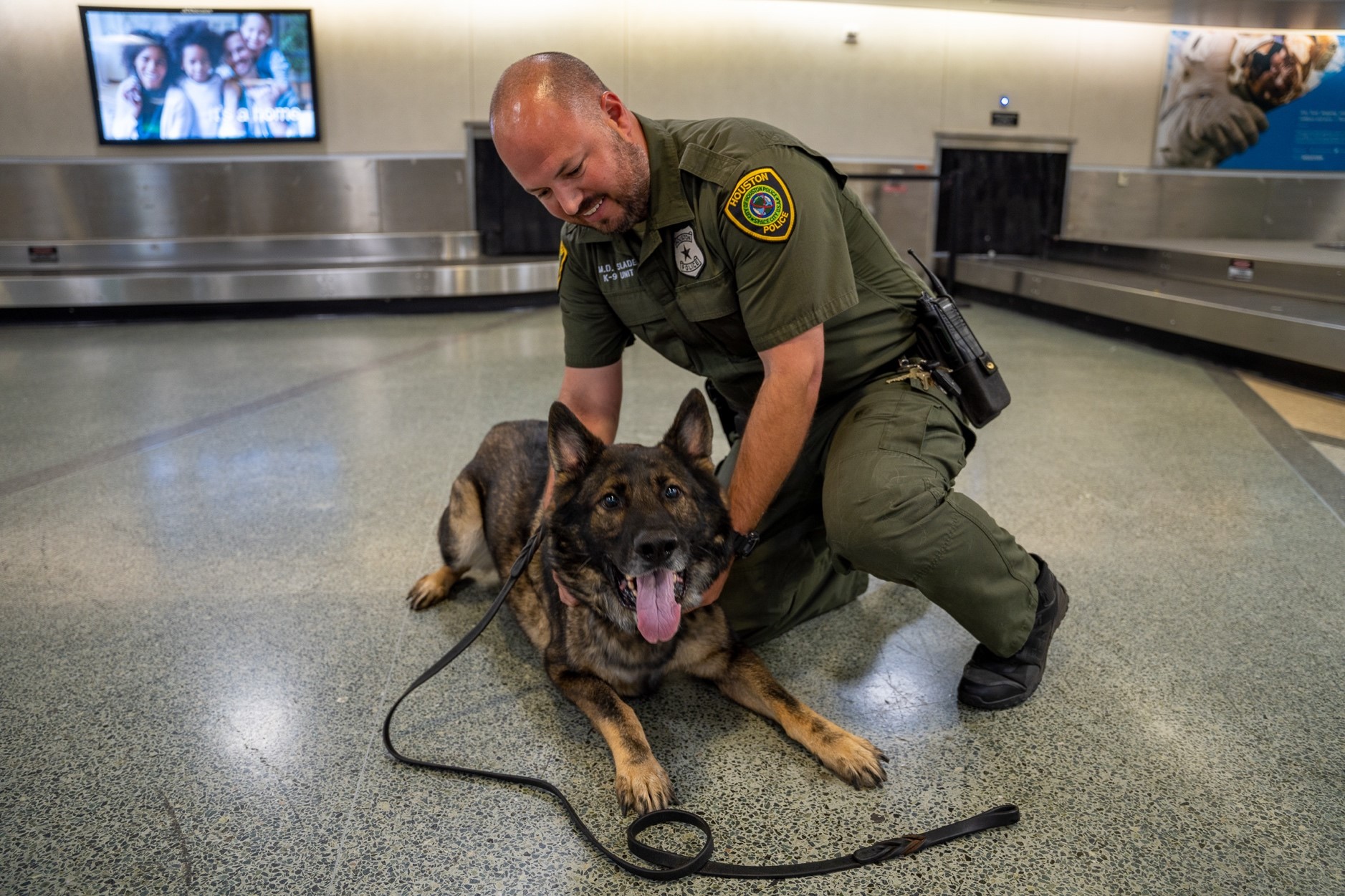 Photo showing a Houston Police officer rubbing the belly of his K9 partner at George Bush Intercontinental Airport