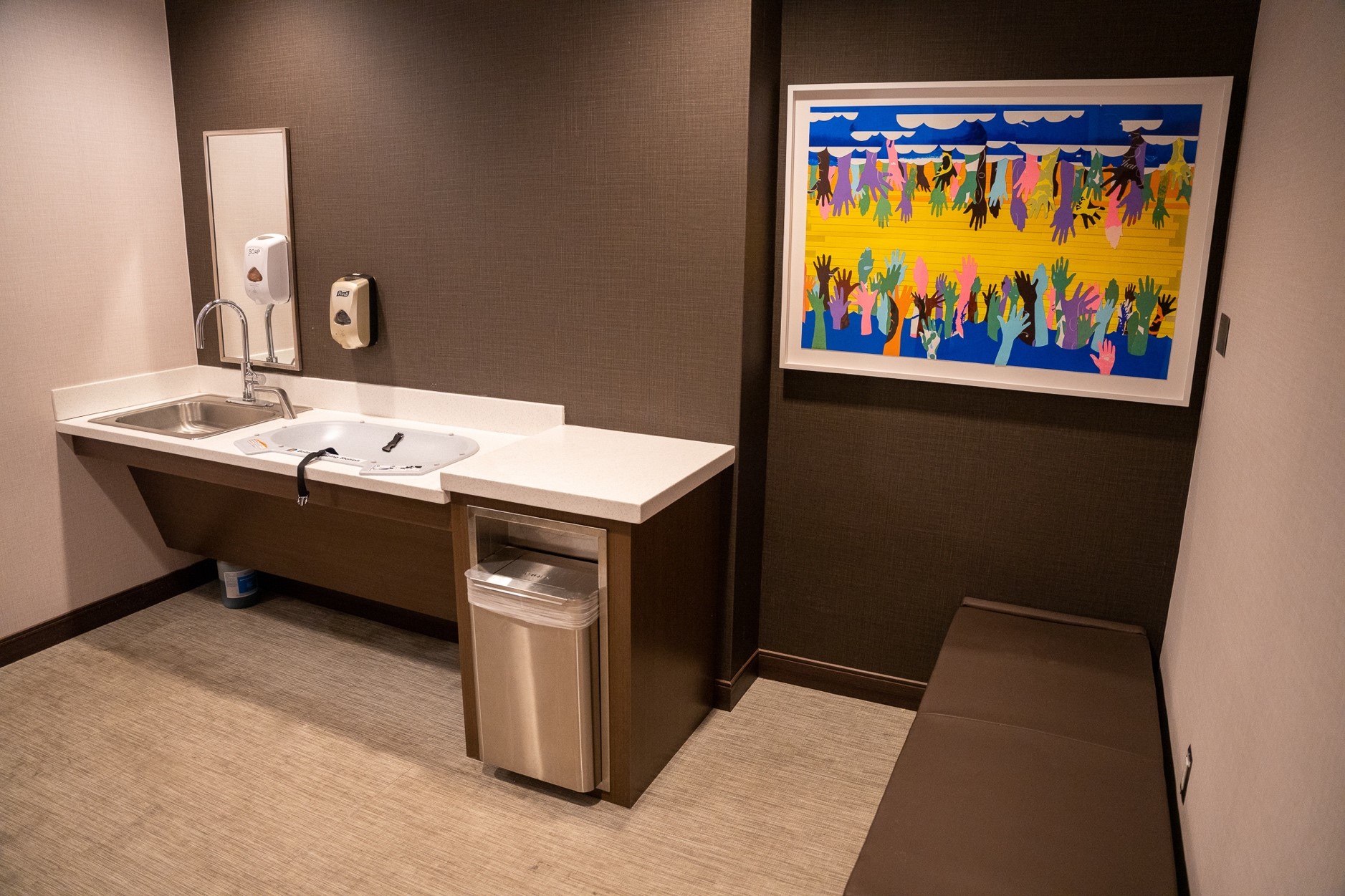 Photo shows private nursing room at a Houston airport. Baby changing station, sink, trashcan and comfortable seating are available for free to parents traveling with young children.